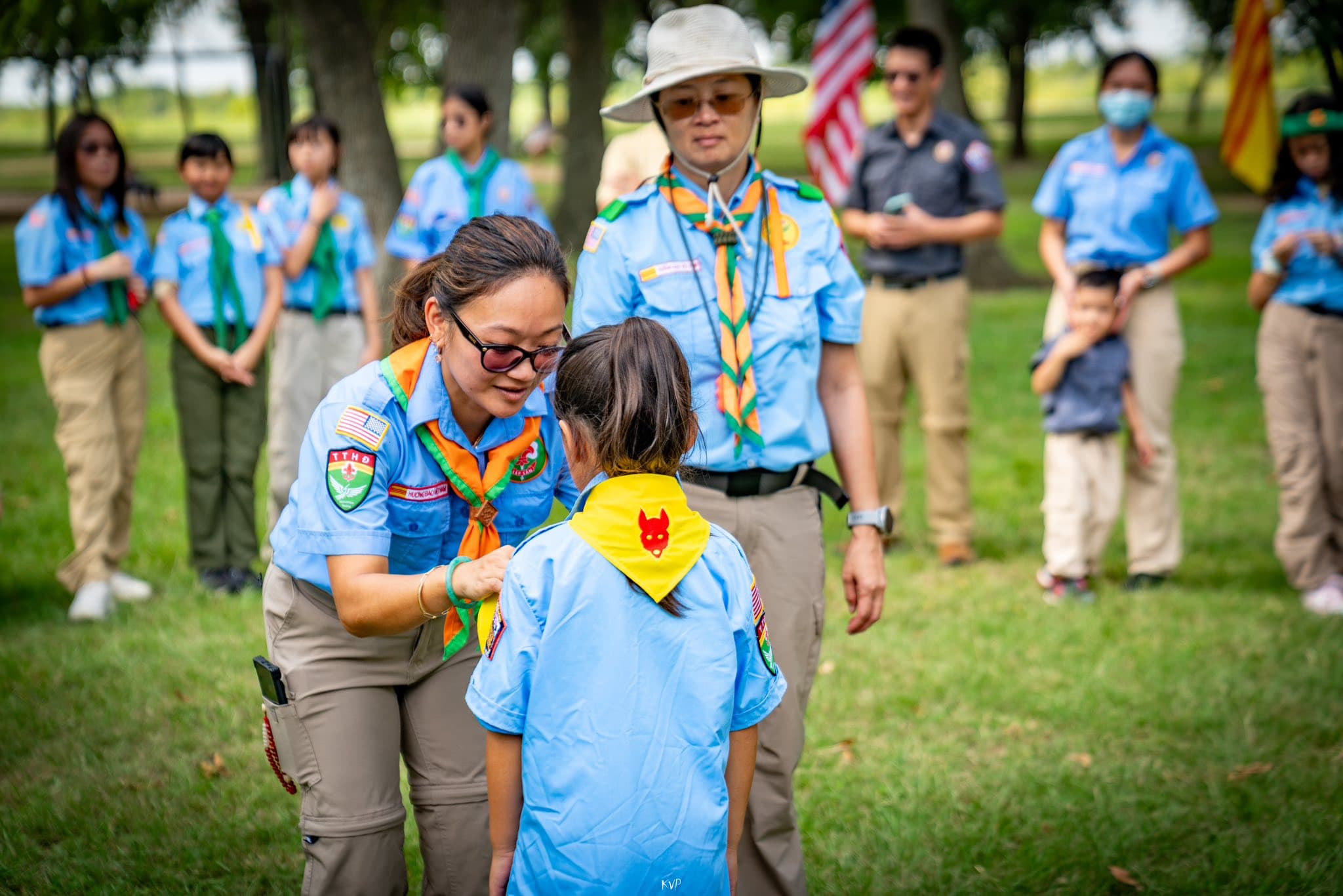 A trưởng adjusts a young scout's neckerchief during a ceremony