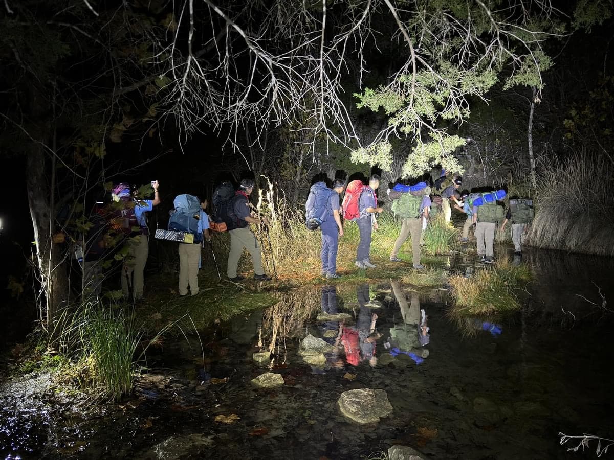 Scouts crossing a creek by headlamp on a night hike